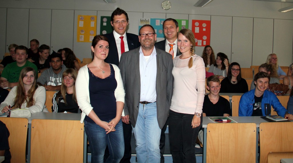 Auf dem Foto sehen Sie: Jürgen Wöllmer von der Fachakademie Hensoltshöhe mit zwei seiner Studentinnen, Walter Niederlöhner Raiffeisenbank) und Stefan Meier (Wirtschaftsjunioren); im Hintergrund ein Teil der Schüler der 11. Klassen